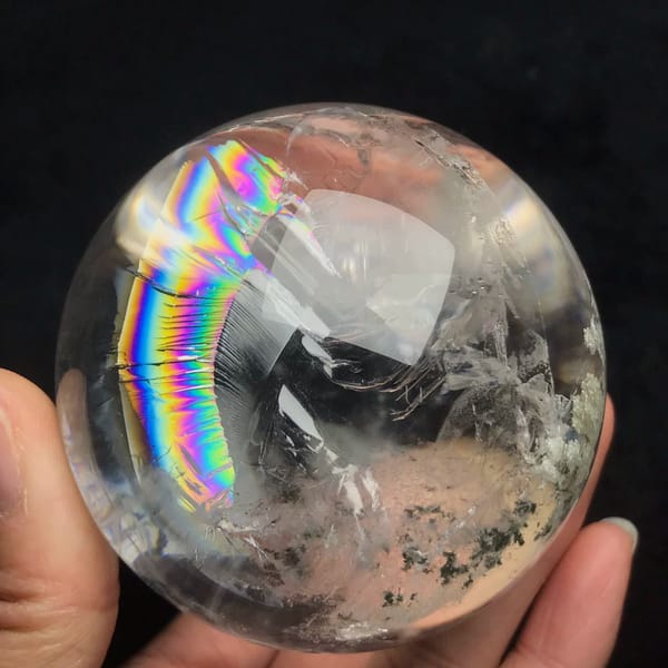 Vertical rainbow arc beside green moss-like phantom clusters