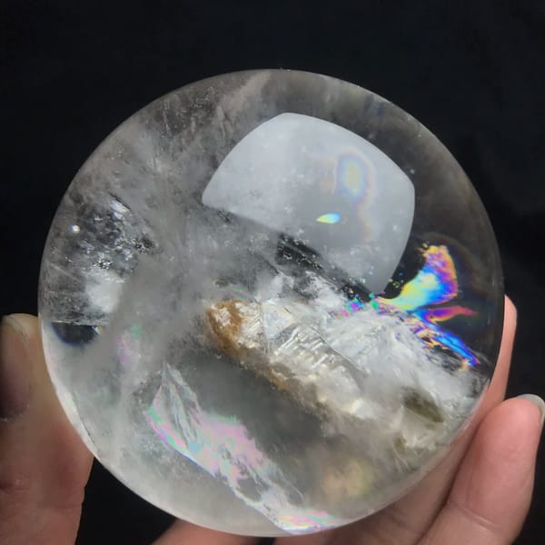 Skeletal crystal lying sideways with a rainbow at its tip
