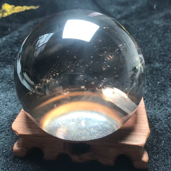 Smoky quartz half sphere resting on a carved wooden stand