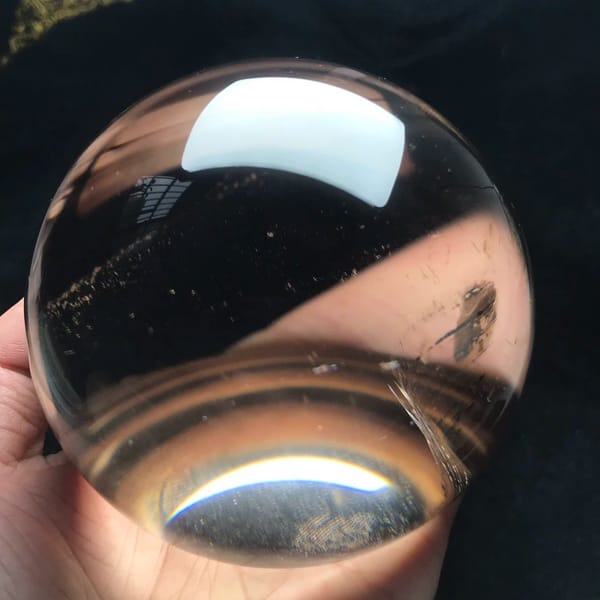 Clear smoky dome held in hand showing glittering specks inside
