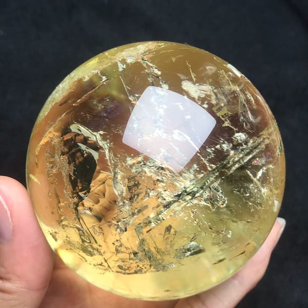 Crackled white veils catching light across the citrine sphere