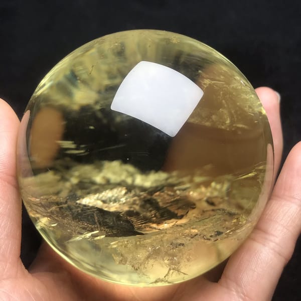 Layered white inclusions glinting in the warm golden quartz of the sphere