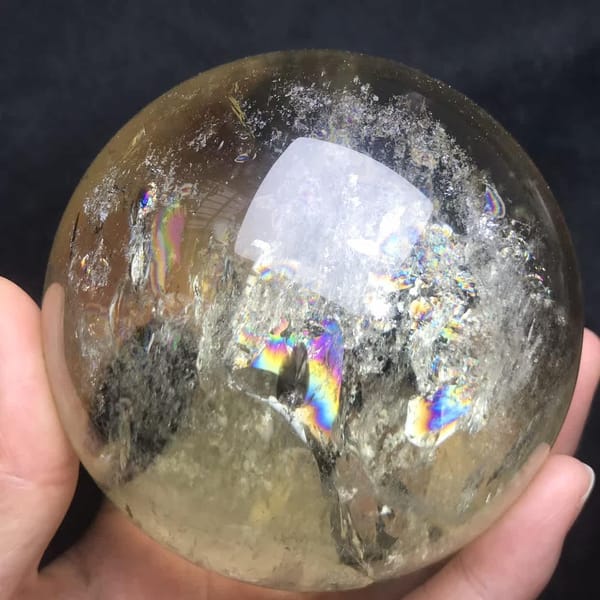 Frosty white veils across the top of the citrine with small rainbows