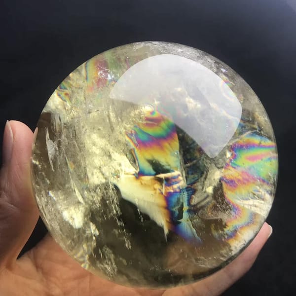 Rainbow streaks and pale veils across the citrine sphere