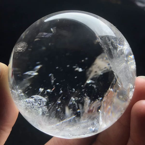 Clear quartz sphere with dark mica flakes and white feather veils