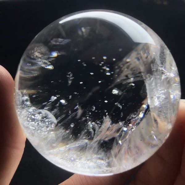 Scattered mica flakes floating at different depths in clear quartz