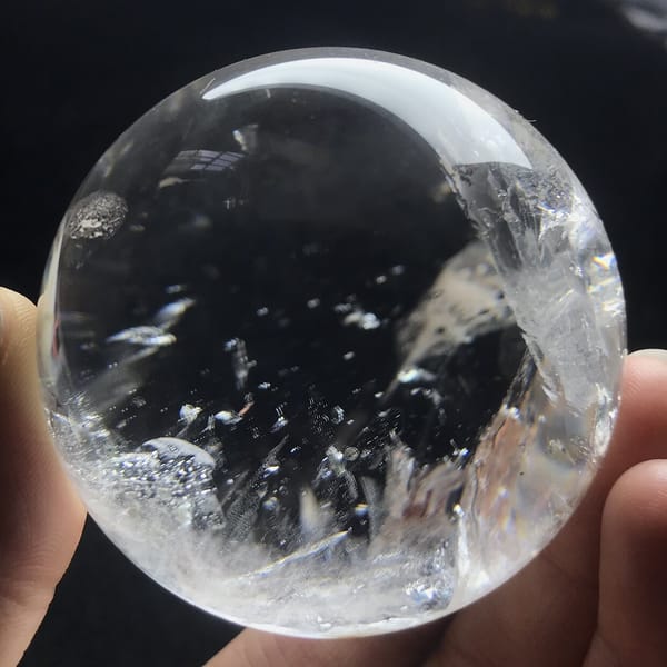 Round dark mica flake near the left edge of the clear sphere