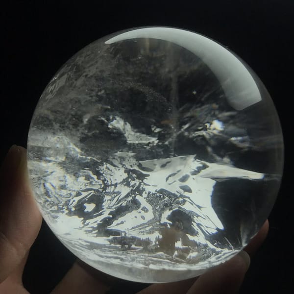 Bright white inclusion patches spreading horizontally through the clear sphere