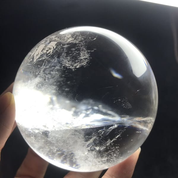 Single sweeping white veil crossing the otherwise clear quartz sphere