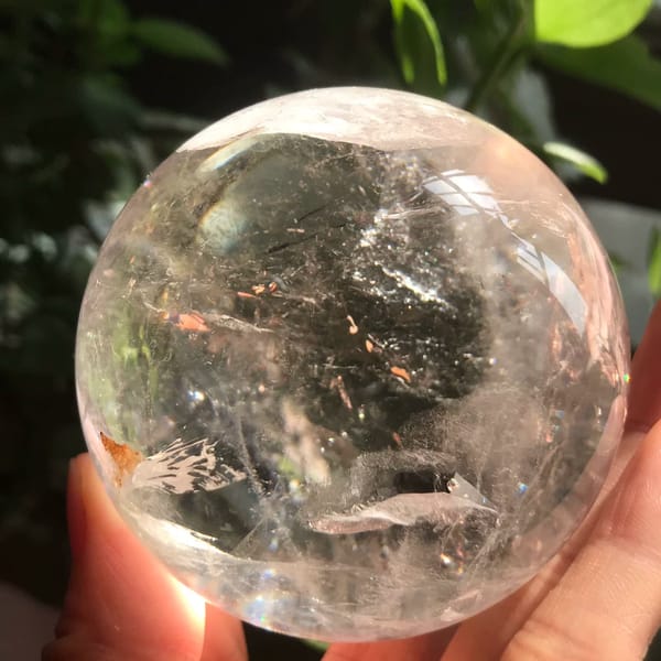 Clear quartz enhydro sphere in sunlight with fine needles and veils