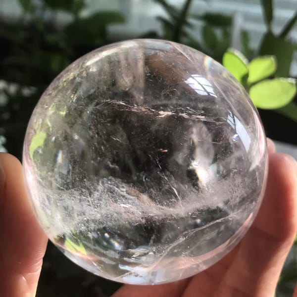 Clear quartz sphere with misty veils against a shaded background