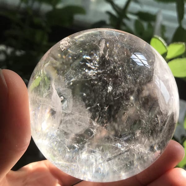 Clear upper dome and silvery inclusions in the enhydro quartz sphere