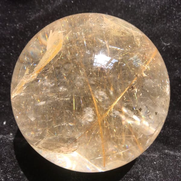 Golden rutile strands crossing at sharp angles inside the Brazilian sphere