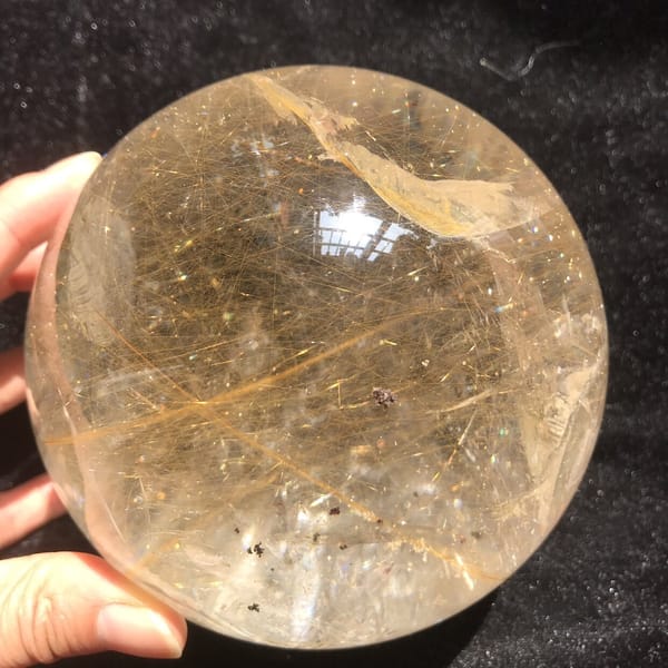 Golden needles and small dark specks seen through the polished quartz