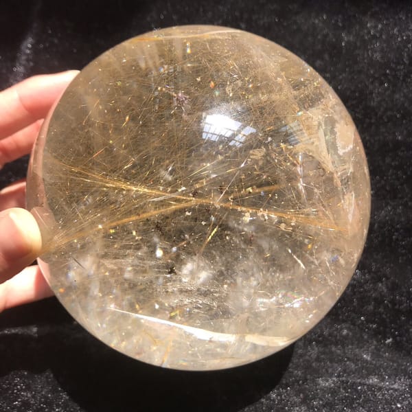 Shimmering gold rutile layers inside the large sphere under bright light