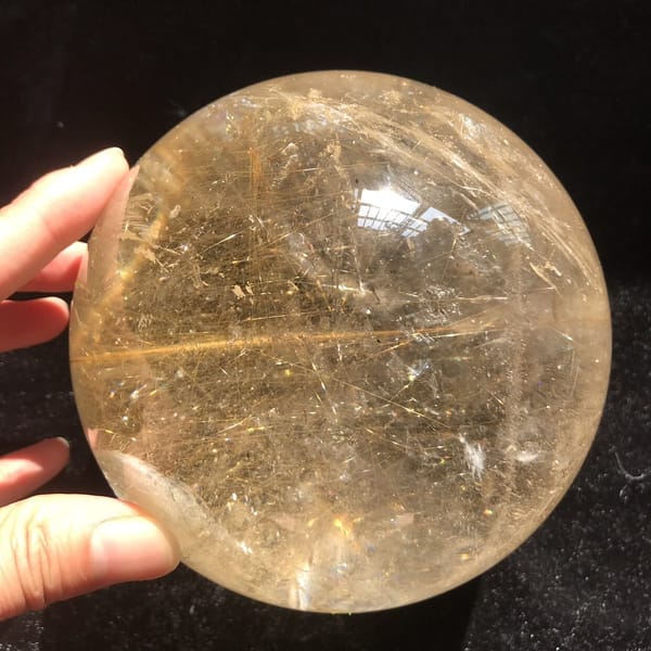 Sphere held in fingers with golden needles running edge to edge