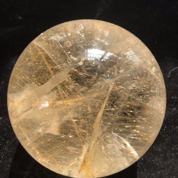 Bold rutile strand slanting through the lower half of the sphere