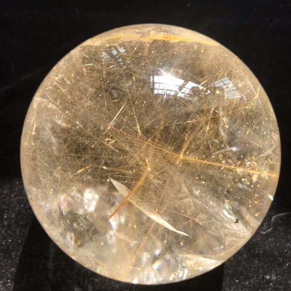 Tangled fine rutile threads in warm light against black velvet
