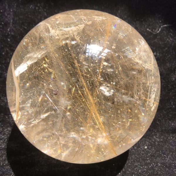 Golden rutile and pale phantom-like veils inside the large quartz ball