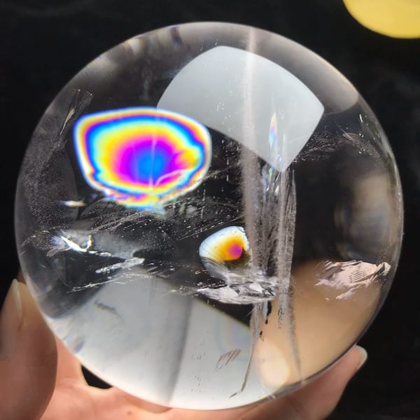Himalayan quartz sphere with a large bullseye rainbow disc and a smaller one beside
