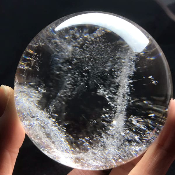 Brazilian clear quartz sphere filled with glittering white specks and a vertical veil