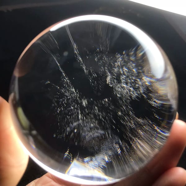 Fine blue-grey inclusion drifts spreading through the clear sphere