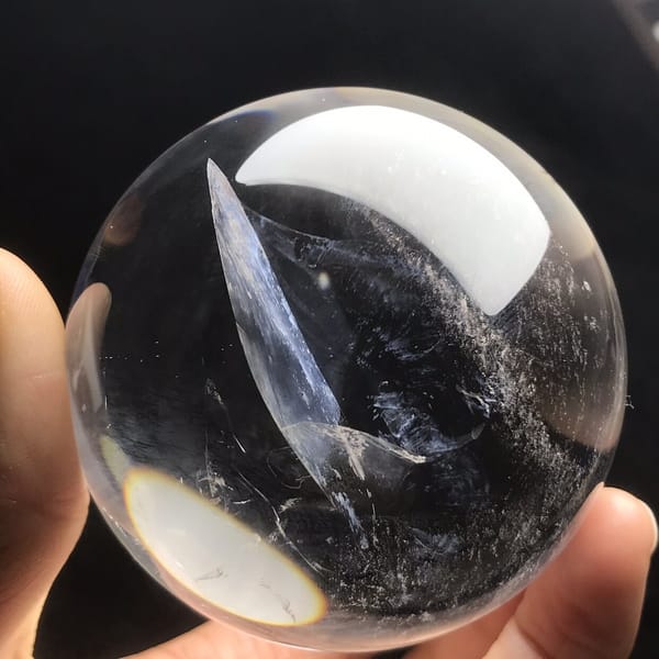 Slender blue-white blade of inclusion leaning across the sphere