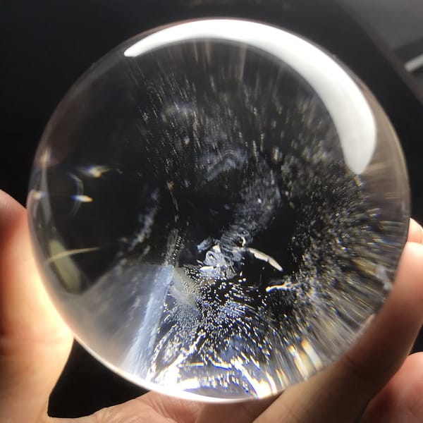 Scattered bluish inclusions throughout the very clear quartz ball