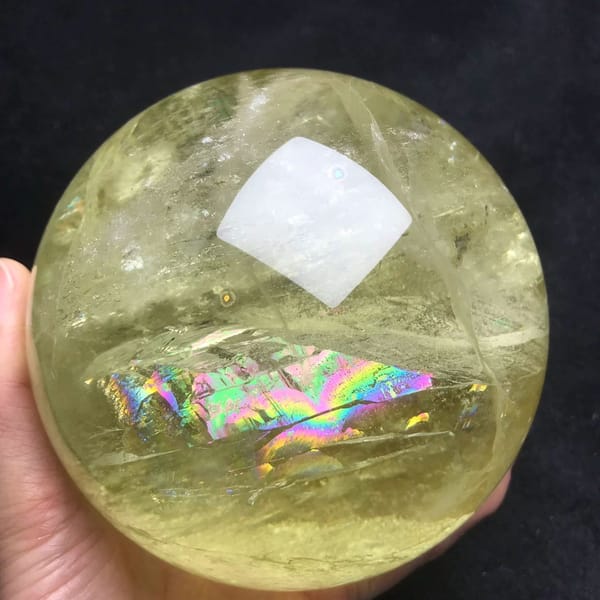 Large lemon-yellow citrine sphere with a wide rainbow plane across the lower half