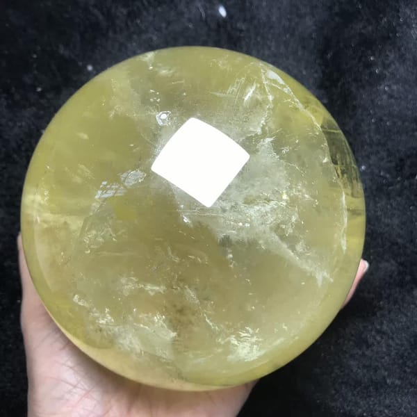Large citrine sphere on dark fabric under bright overhead light