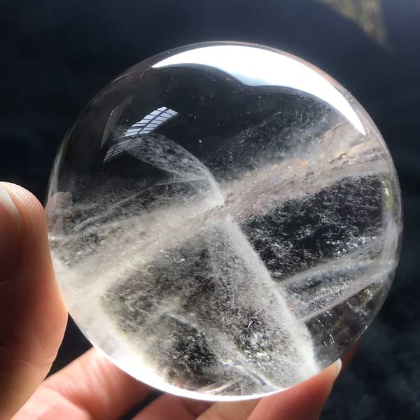 Light smoky quartz sphere with misty veils crossing in an X
