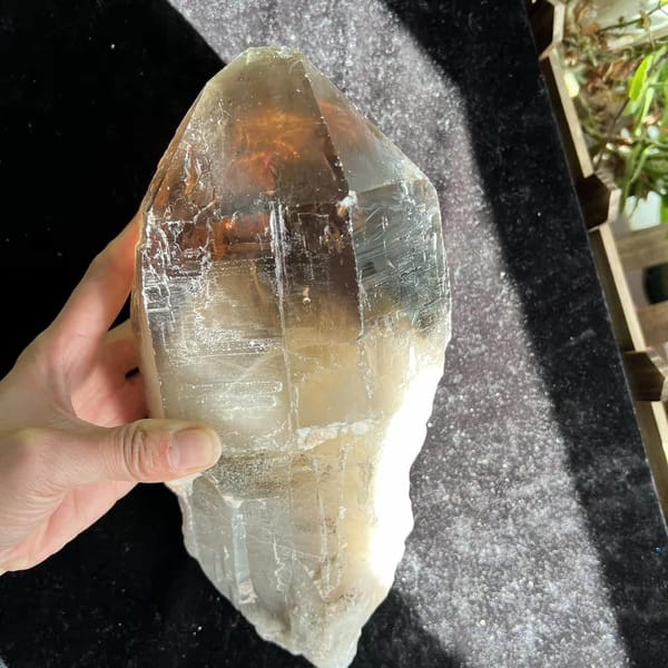 Backlit smoky quartz in hand revealing the white misty internal mountain
