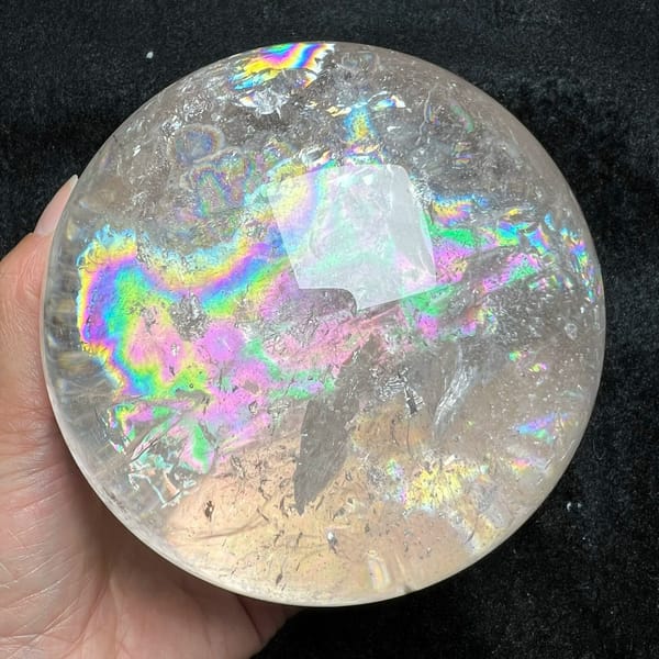 Wide rainbow stretching sideways across the sphere with white veils