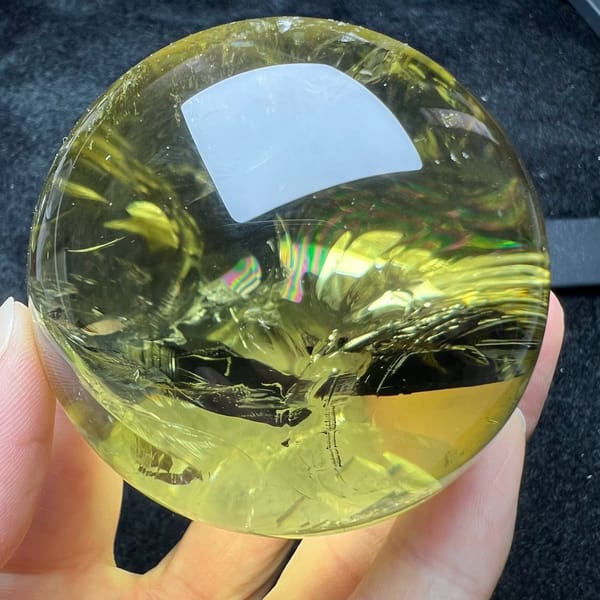 Citrine sphere with flowing honey veils and a soft rainbow near the top