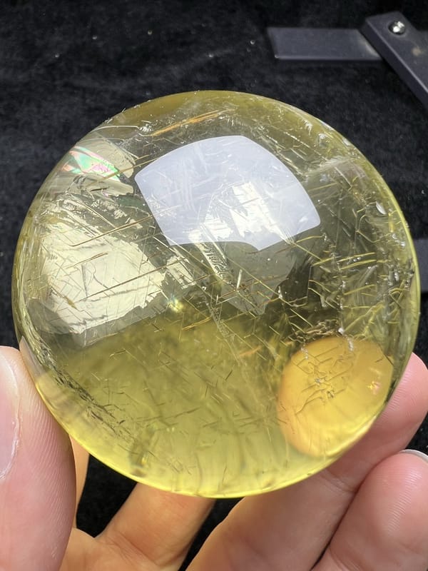 Citrine sphere with a golden net of fine lines and a rainbow flash