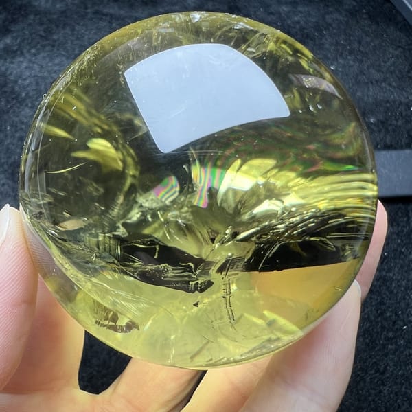 Rainbow glints along a healed plane inside the yellow citrine ball