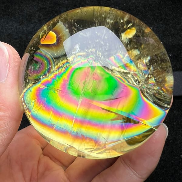 Citrine sphere in hand with concentric rainbow rings and a green centre