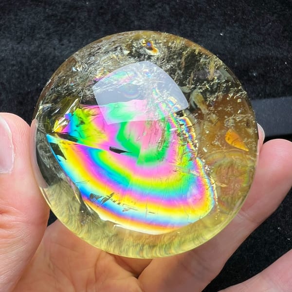 Smaller rainbow rings framed by the bright reflection on the citrine