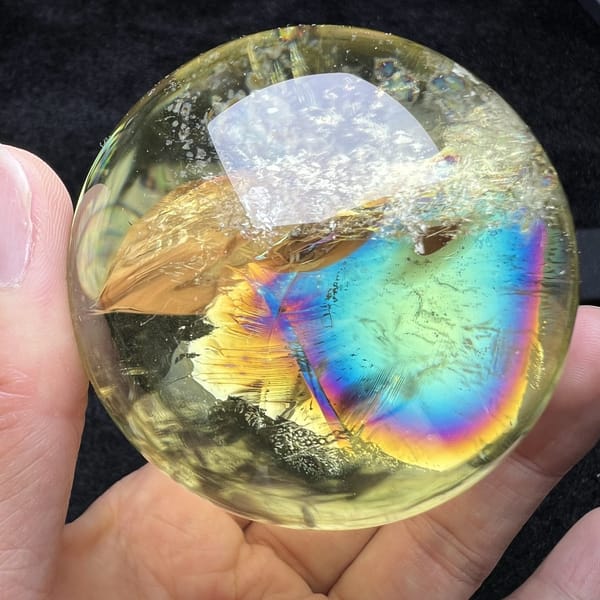 Blue-green rainbow next to a golden feather inclusion in the sphere