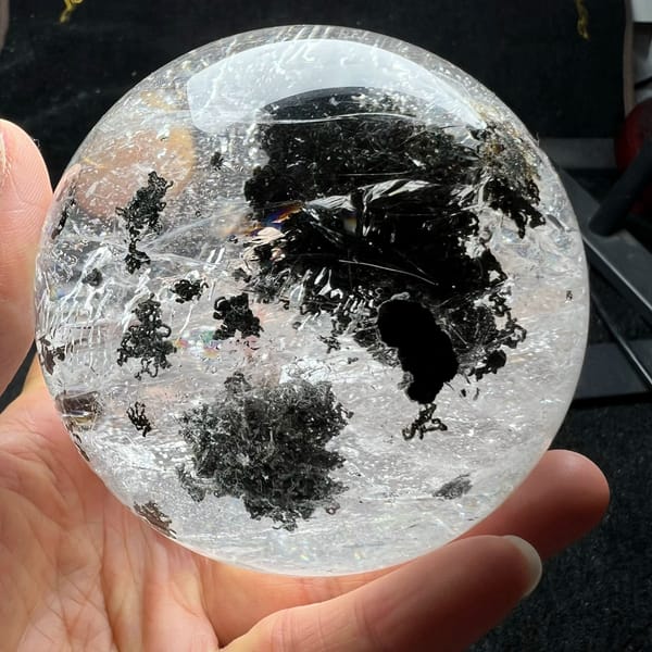 Several dark green phantom tufts scattered across the polished quartz