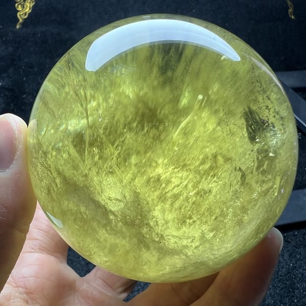 Lemon citrine sphere angled to show veils sweeping from the base