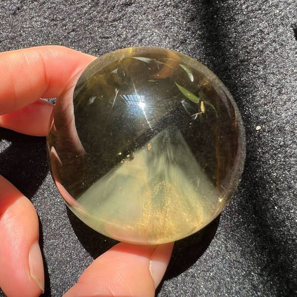 Citrine ball held at an angle with the pyramid and fine needle streaks