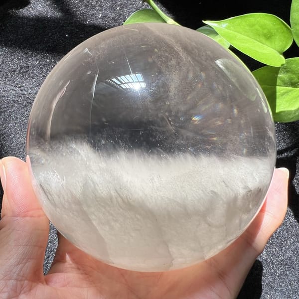 Sphere beside green leaves showing its clear top and snowy base