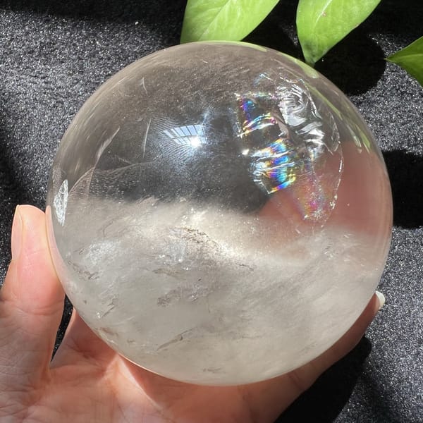 Small rainbow flashing near the top of the clear quartz sphere