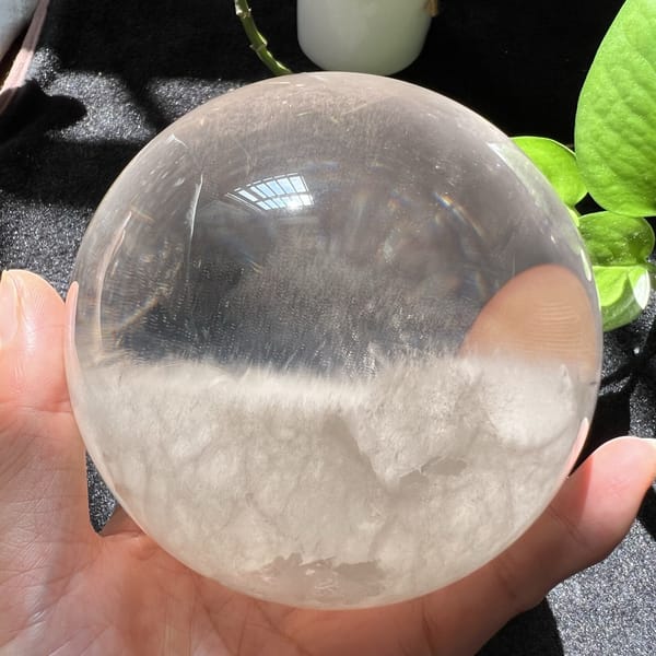 Large quartz cloud sphere held in front of green plant leaves