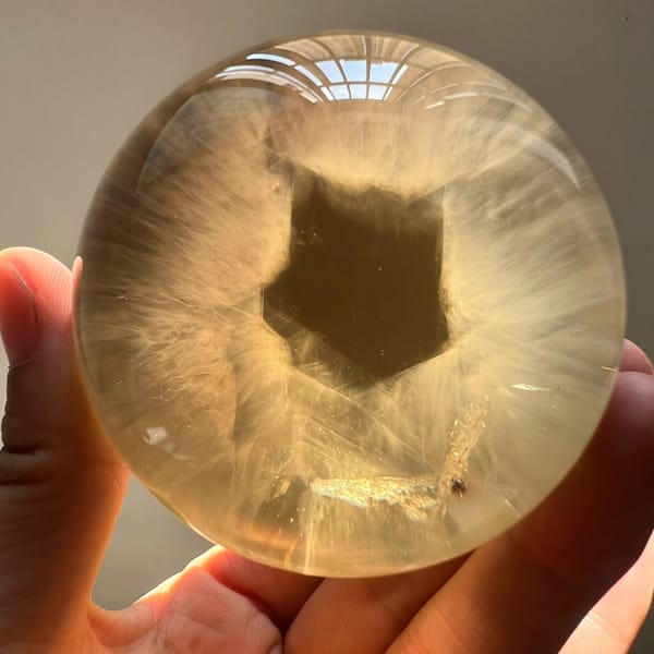 Top-down view of the citrine sphere with white needles radiating round a dark window