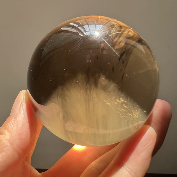 Citrine sphere angled to show the broad needle peak and clear sky above