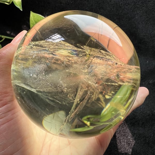 Layered golden veils stretching across the sphere beside green leaves