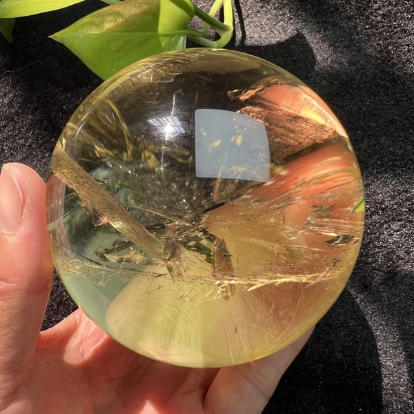 Diagonal veil band and warm glow in the polished citrine sphere