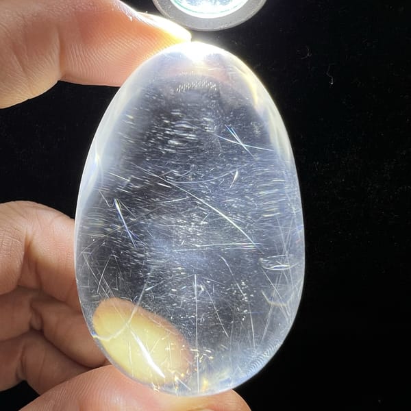 Torch-lit rutilated egg with cool blue haze and frosty needles